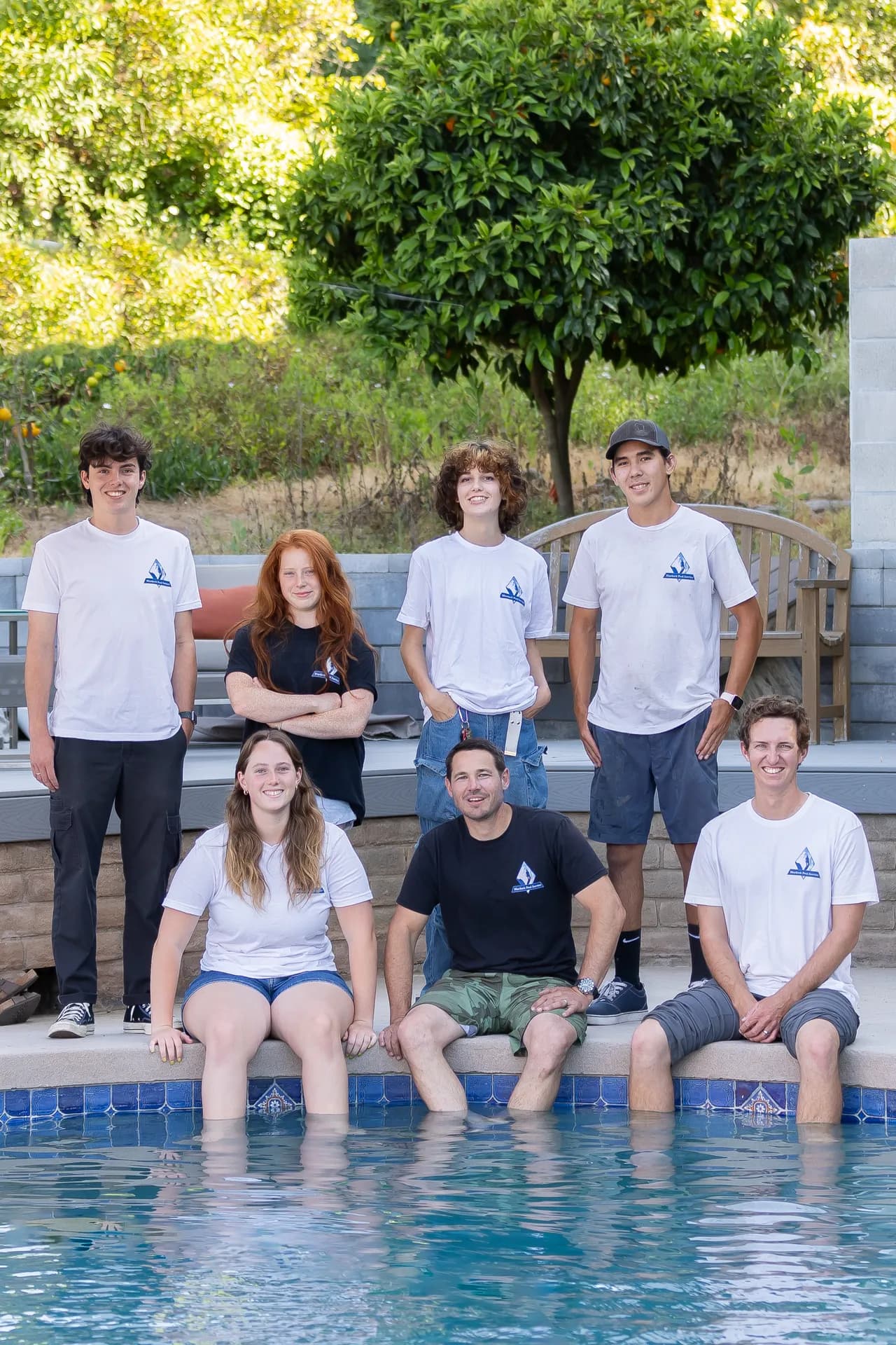 The full Murdock Pool Service team posing by a crystal-clear pool
