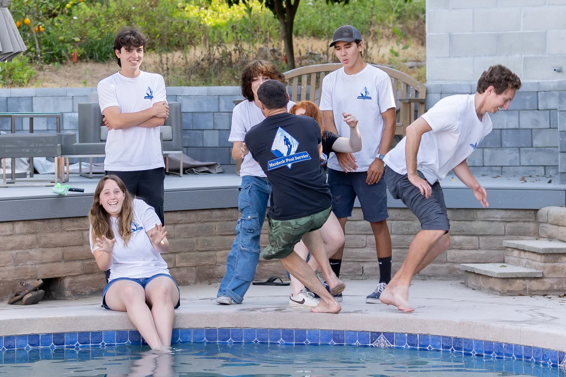 Playful moment as the team pushes each other toward the pool