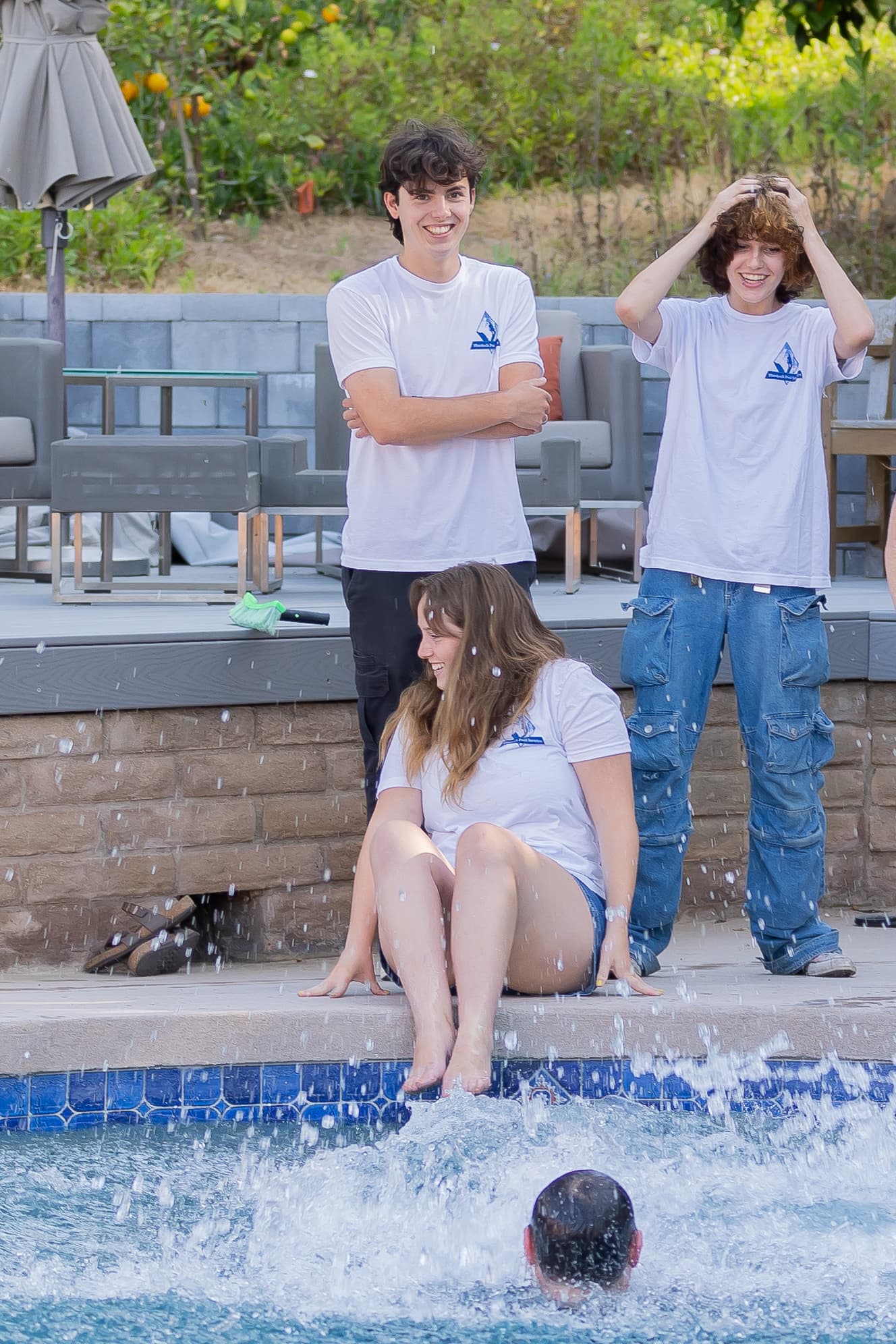 Team members kicking water and having fun at the pool edge