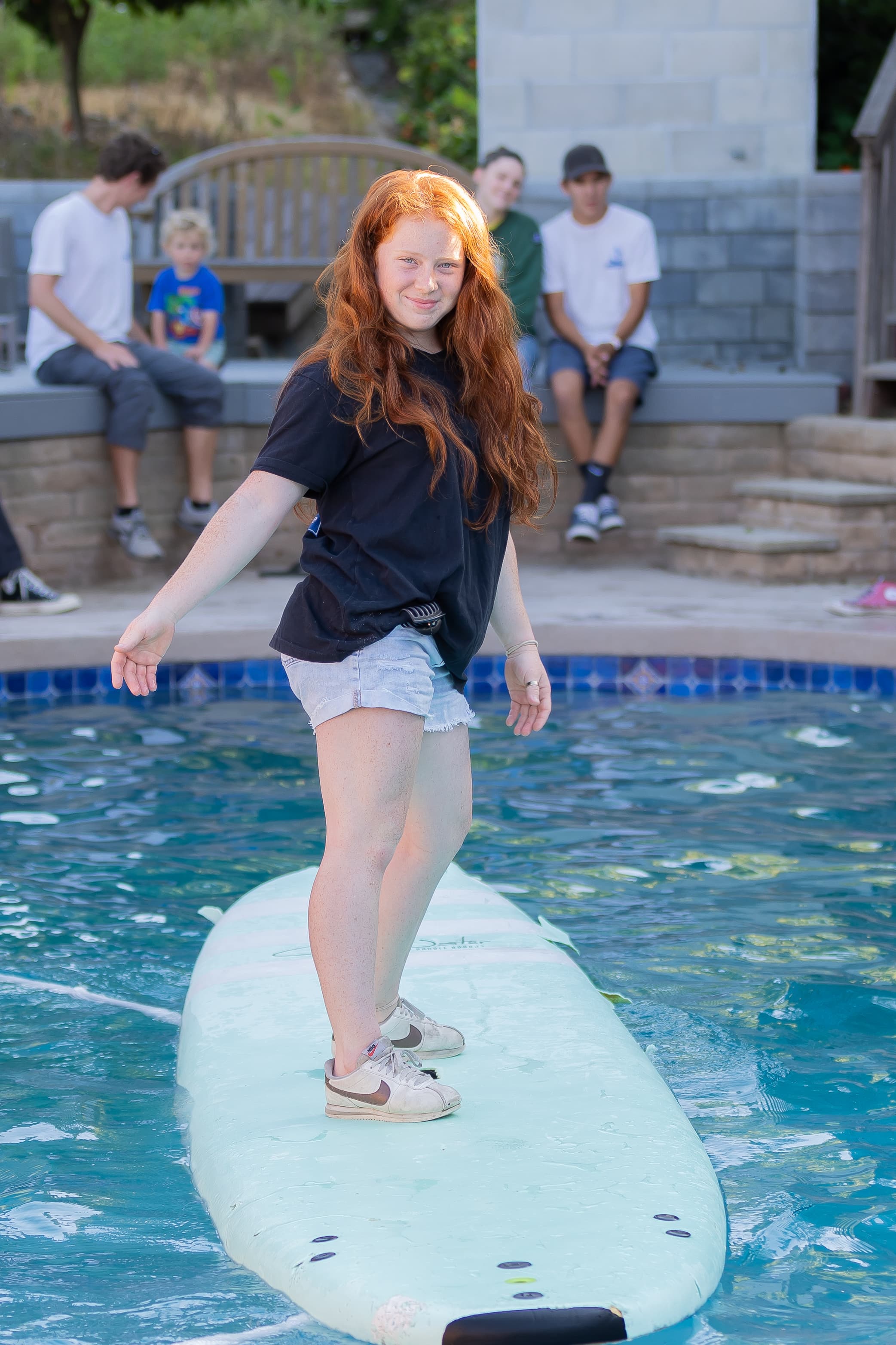 Team member balancing on a surfboard in the pool