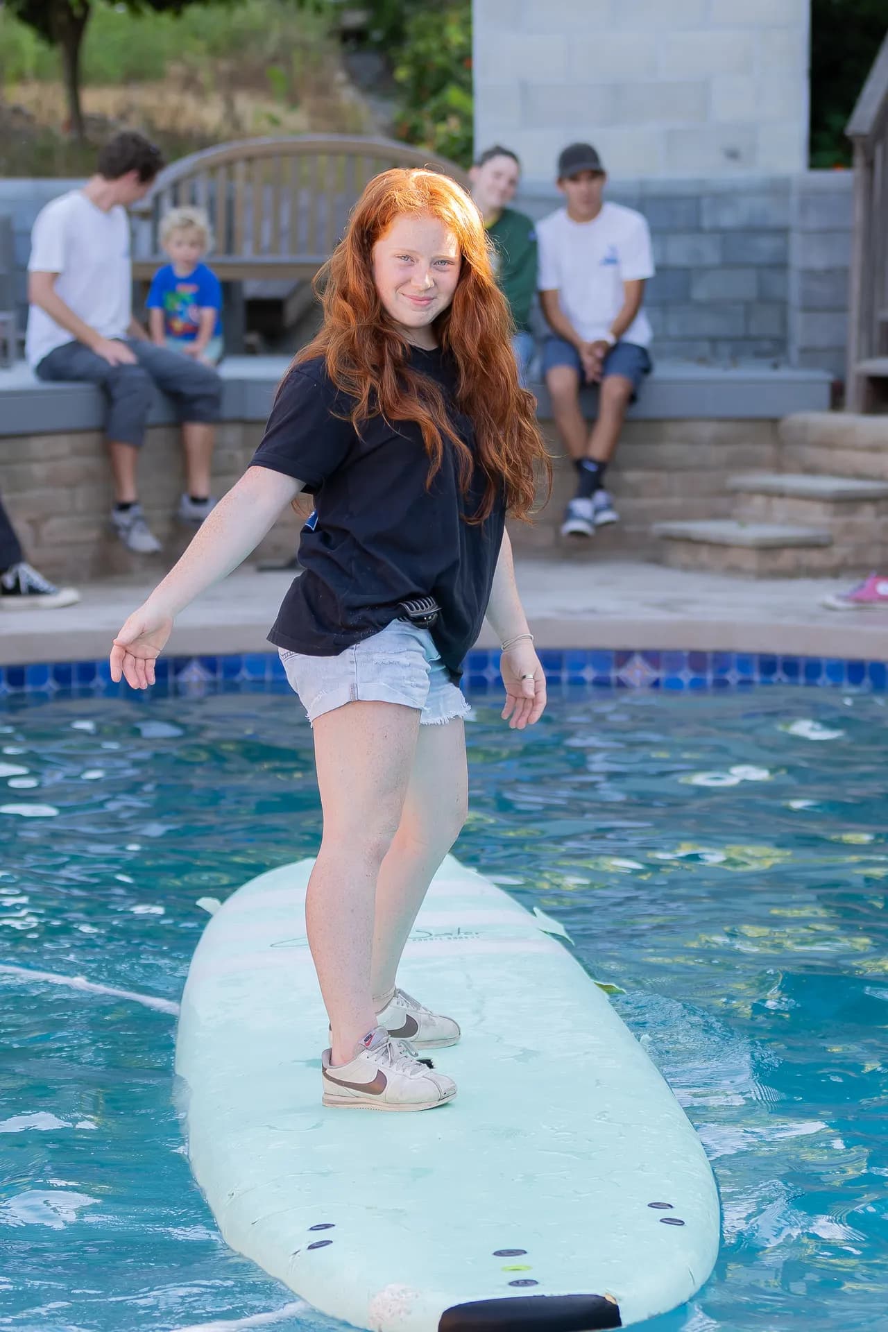 Team member balancing on a surfboard in the pool