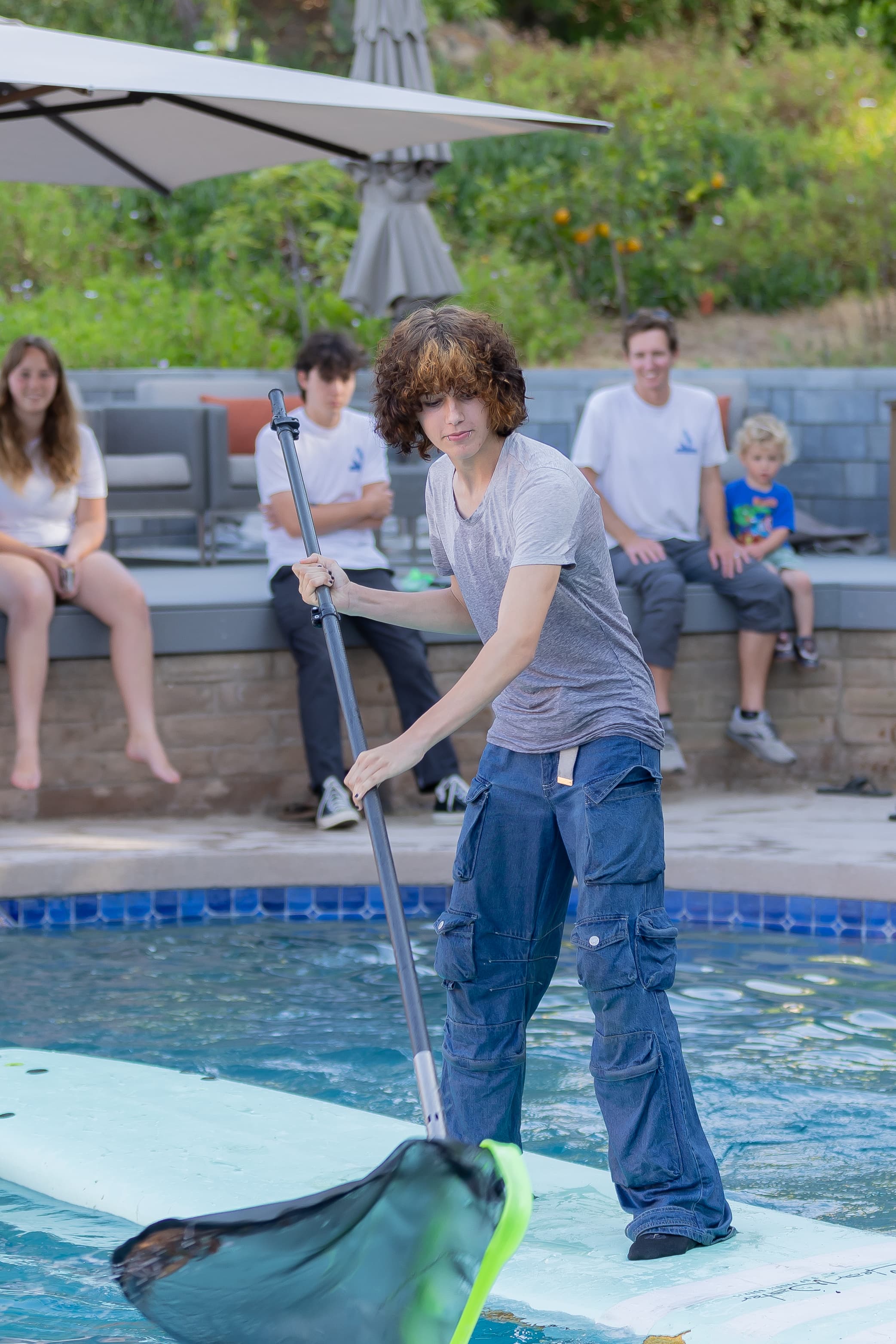 Murdock Pool Service technician skimming a pool during a service visit
