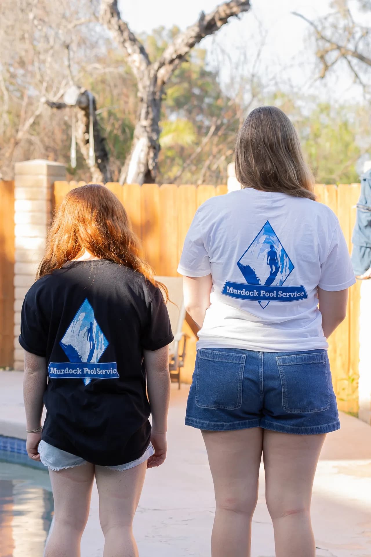 Two team members showing off branded Murdock Pool Service shirts
