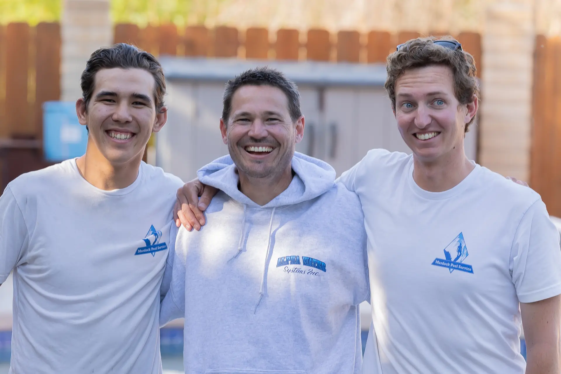 Brett laughing with two team members at a customer pool