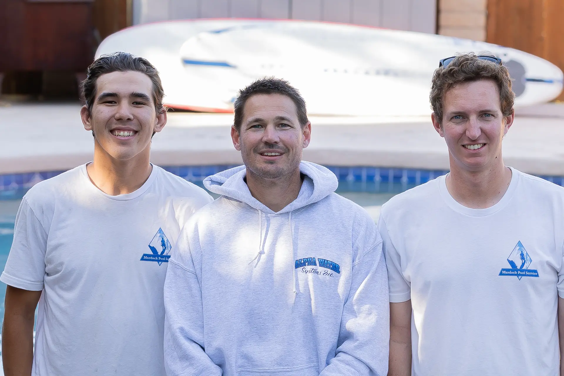 Brett with two team members standing by a paddleboard at a San Diego customer pool