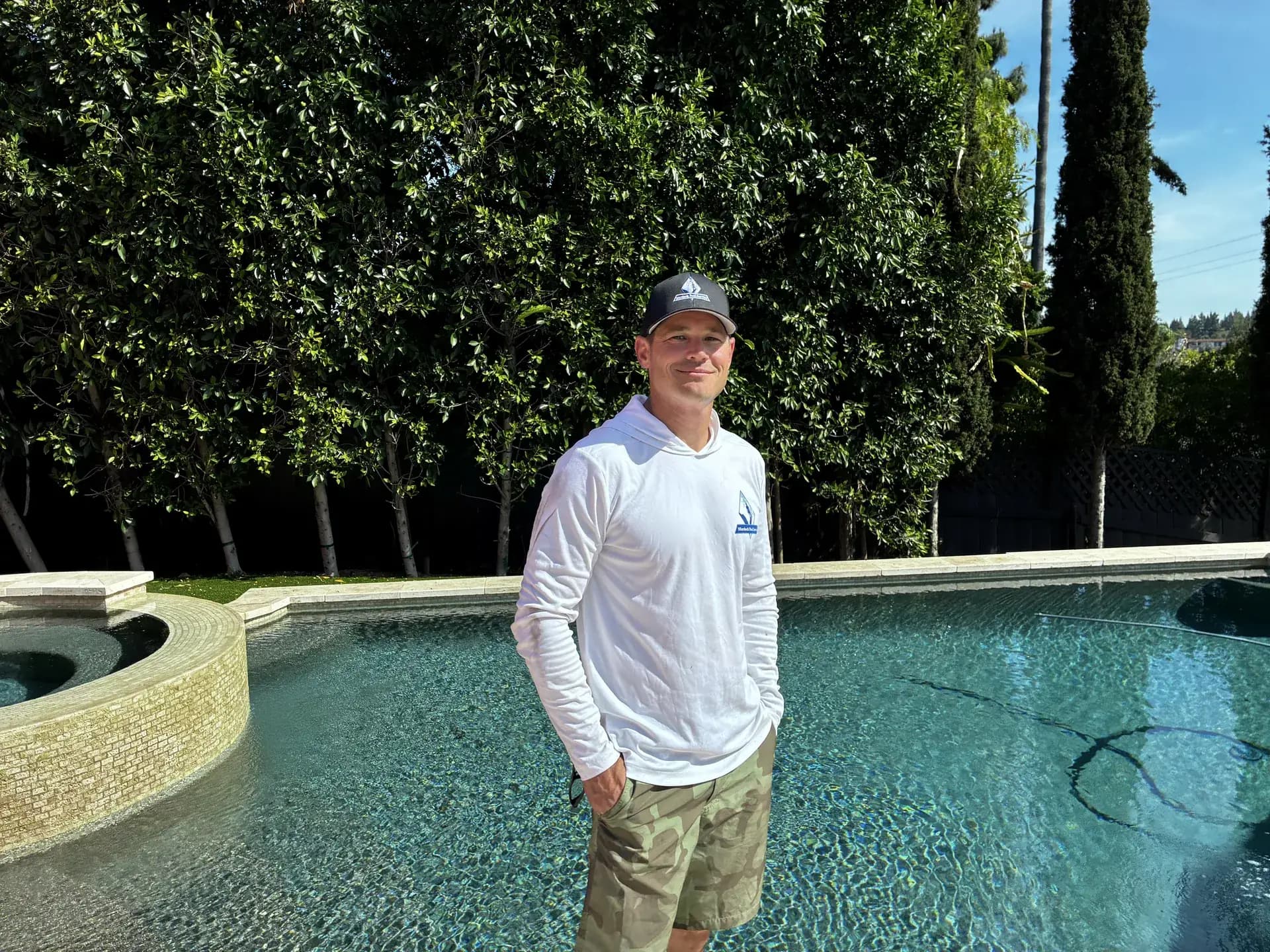 Brett Murdock in branded Murdock Pool Service apparel standing poolside at a San Diego customer property