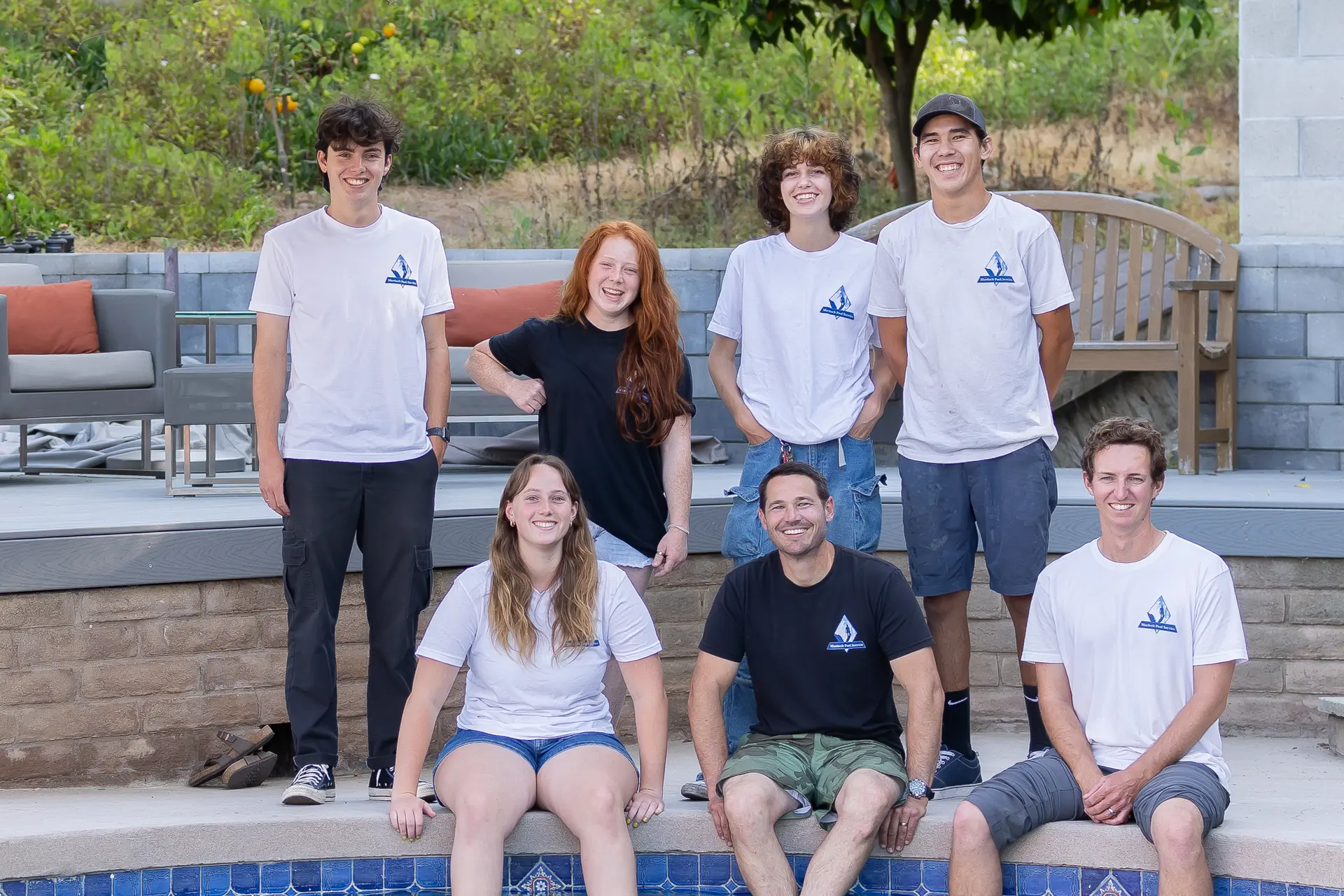 Murdock Pool Service team seated together at the edge of a customer pool