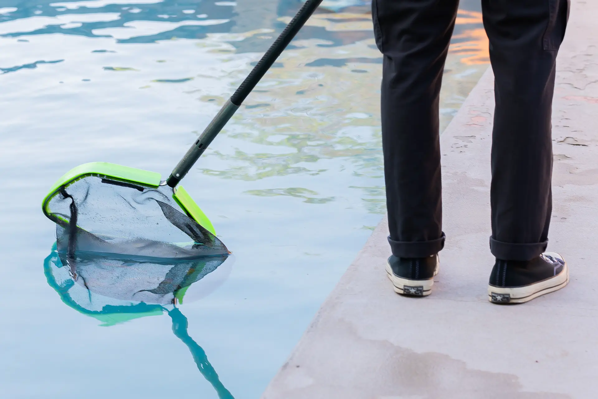 A technician skimming the surface of a customer pool in San Diego