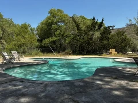 Murdock Pool Service technician working a rustic backyard pool surrounded by oak trees in a La Mesa hillside neighborhood