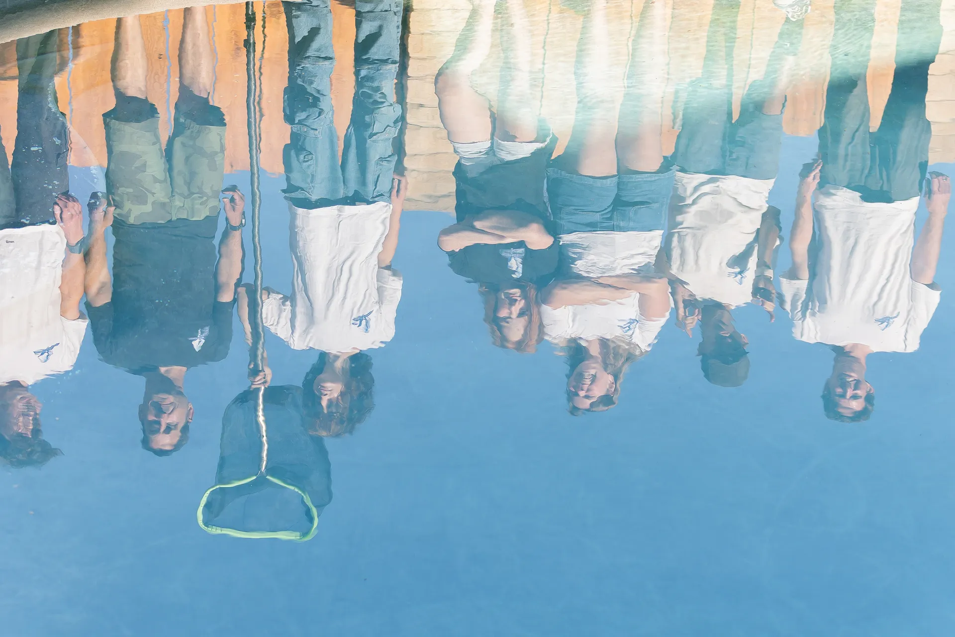 Murdock Pool Service team reflected in the sparkling water of a customer pool after weekly service in Chula Vista